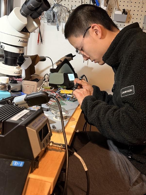 Man at desk soldering a circuit board.